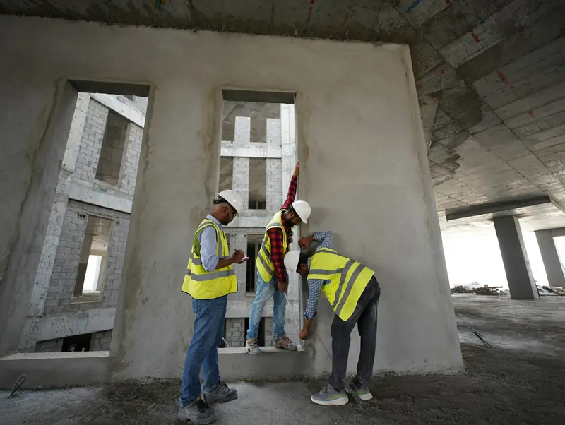 Trois artisans qui prennent des mesures sur un chantier
