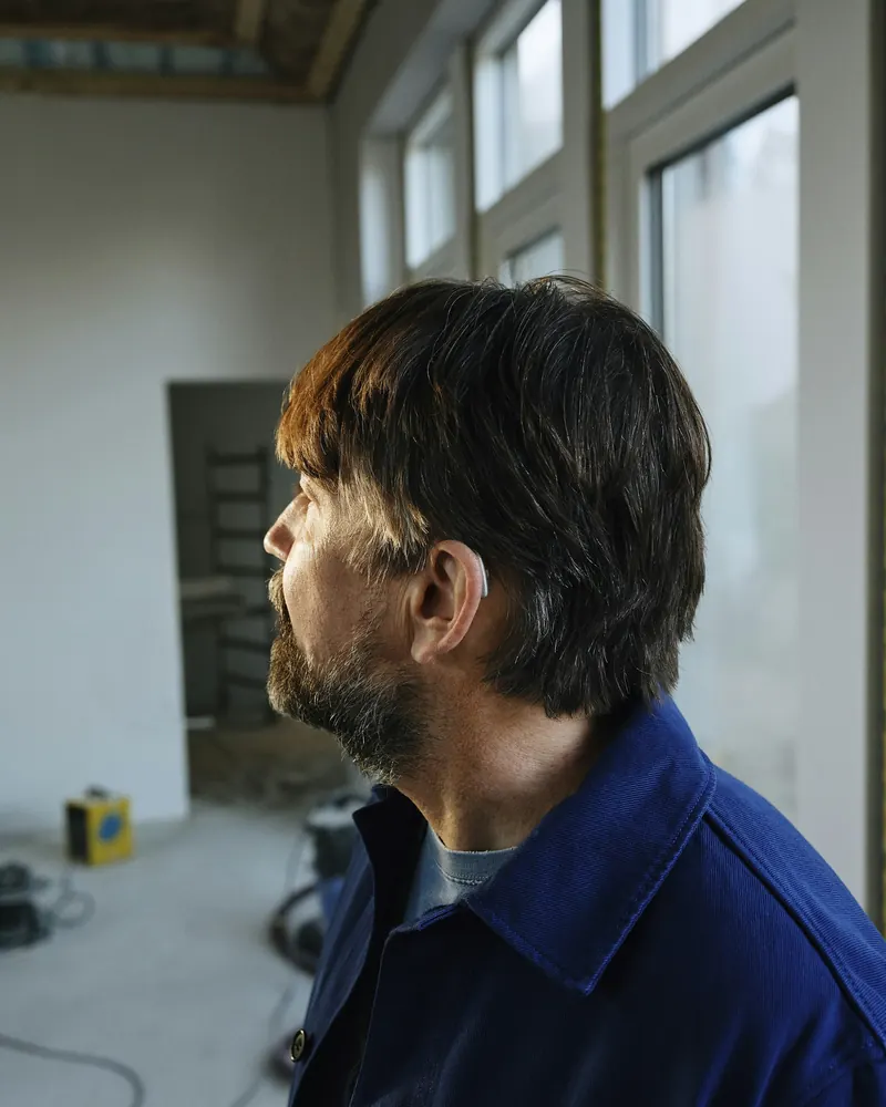 Artisan en veste de travail dans une pièce en travaux